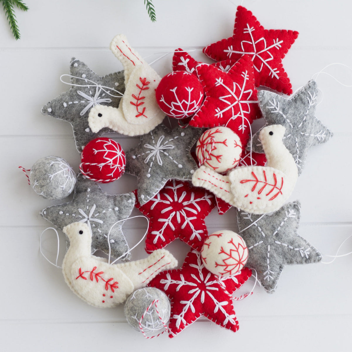 Decorative Christmas ornaments including red and gray stars, snowflakes, and doves on a white background.